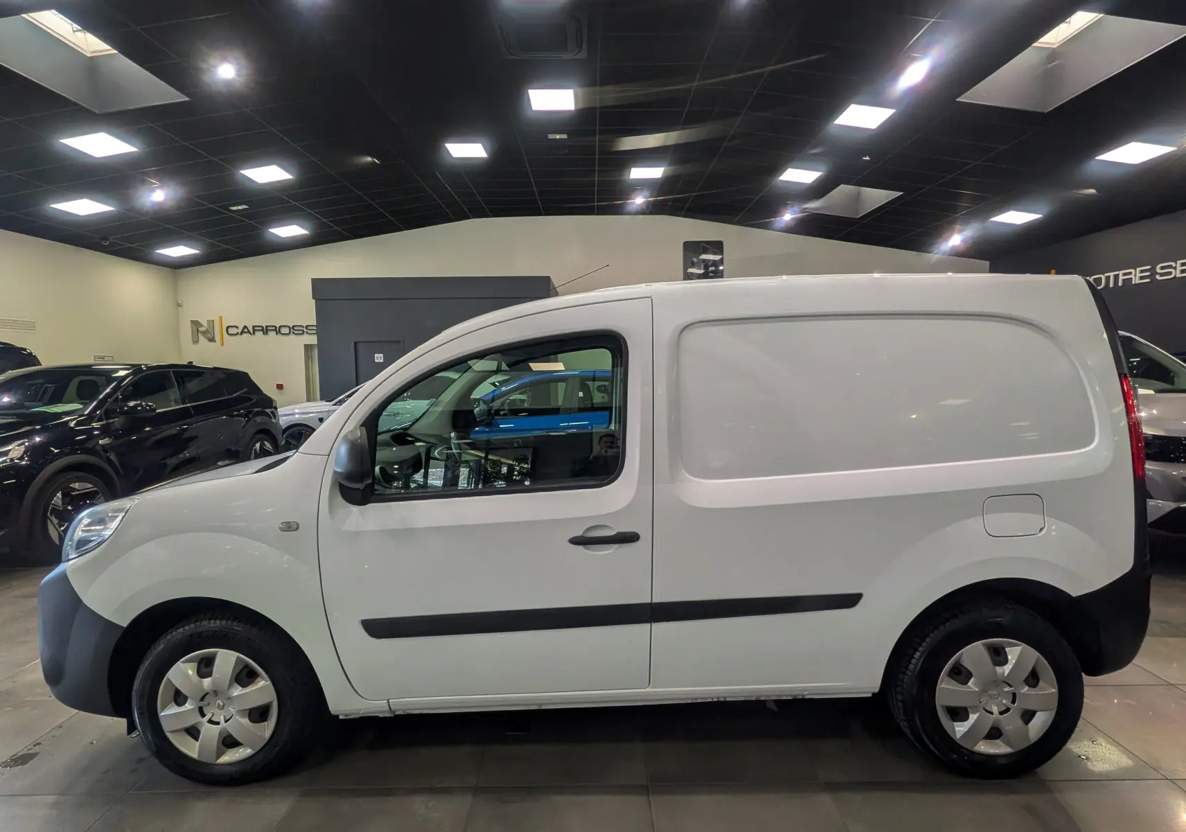 Vue latérale droite d’un Renault Kangoo Express blanc minéral 2020, utilitaire compact avec porte latérale et jantes acier.