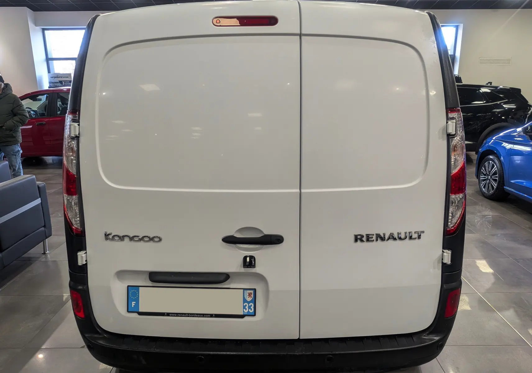 Vue arrière d'un Renault Kangoo Express blanc minéral, montrant les portes battantes et les logos du modèle et de la marque.