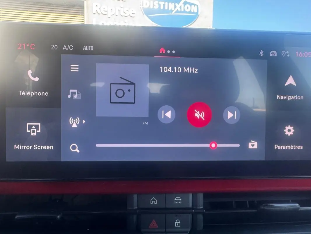 Vue intérieure du tableau de bord du Fiat 600 T-Gen 3 rouge, avec écran tactile multimédia affichant la radio FM.