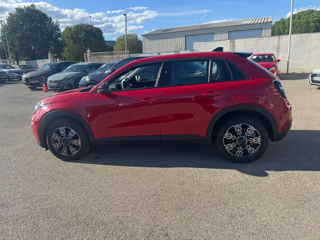 Vue latérale gauche d'une FIAT 600 T-Gen 3 rouge de 2025 avec jantes au design moderne, stationnée en extérieur.