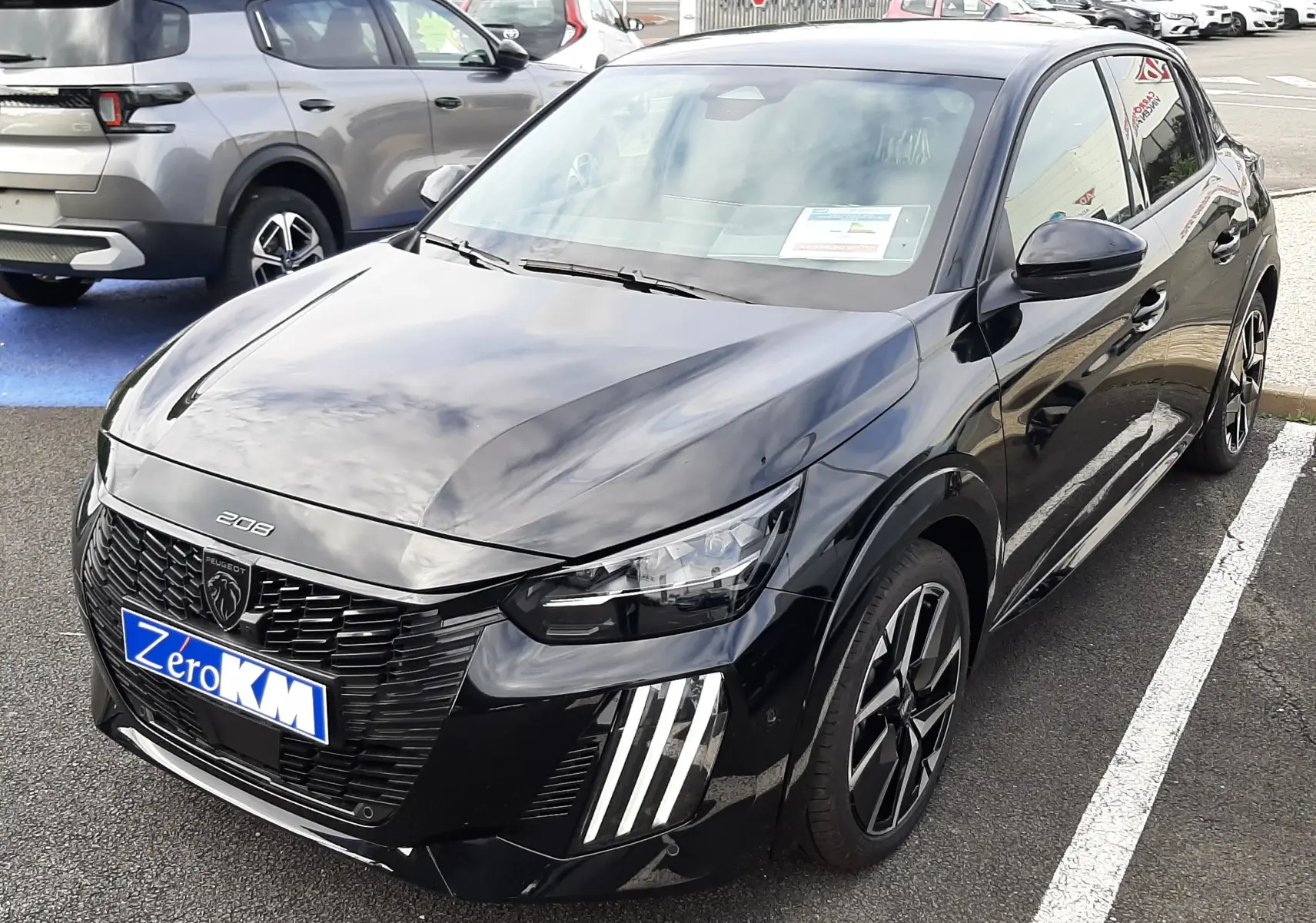 Peugeot 208 Hybrid 145ch GT noire perla vue 3/4 avant droit avec feux LED distinctifs et jantes bi-ton.