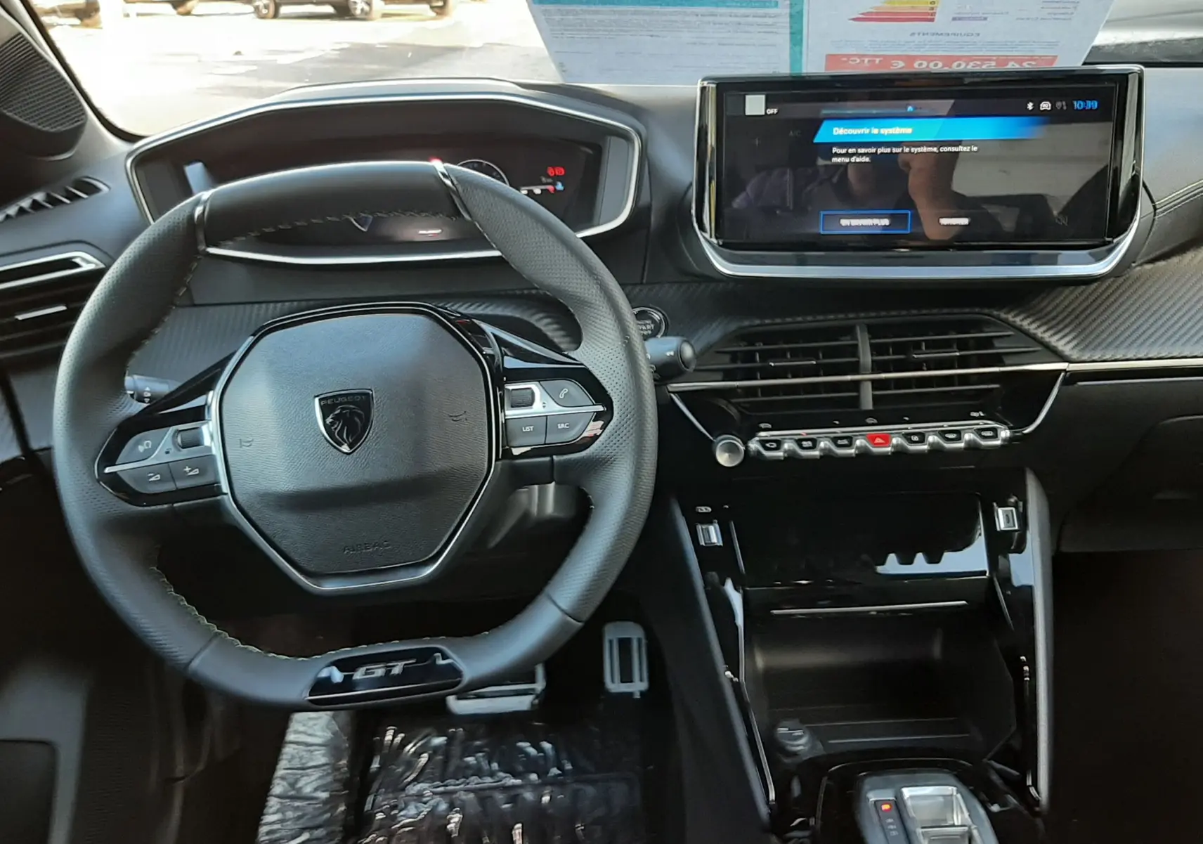 Vue intérieure avant de la Peugeot 208 Hybrid 145ch GT 2026, tableau de bord moderne avec écran tactile et volant GT noir.