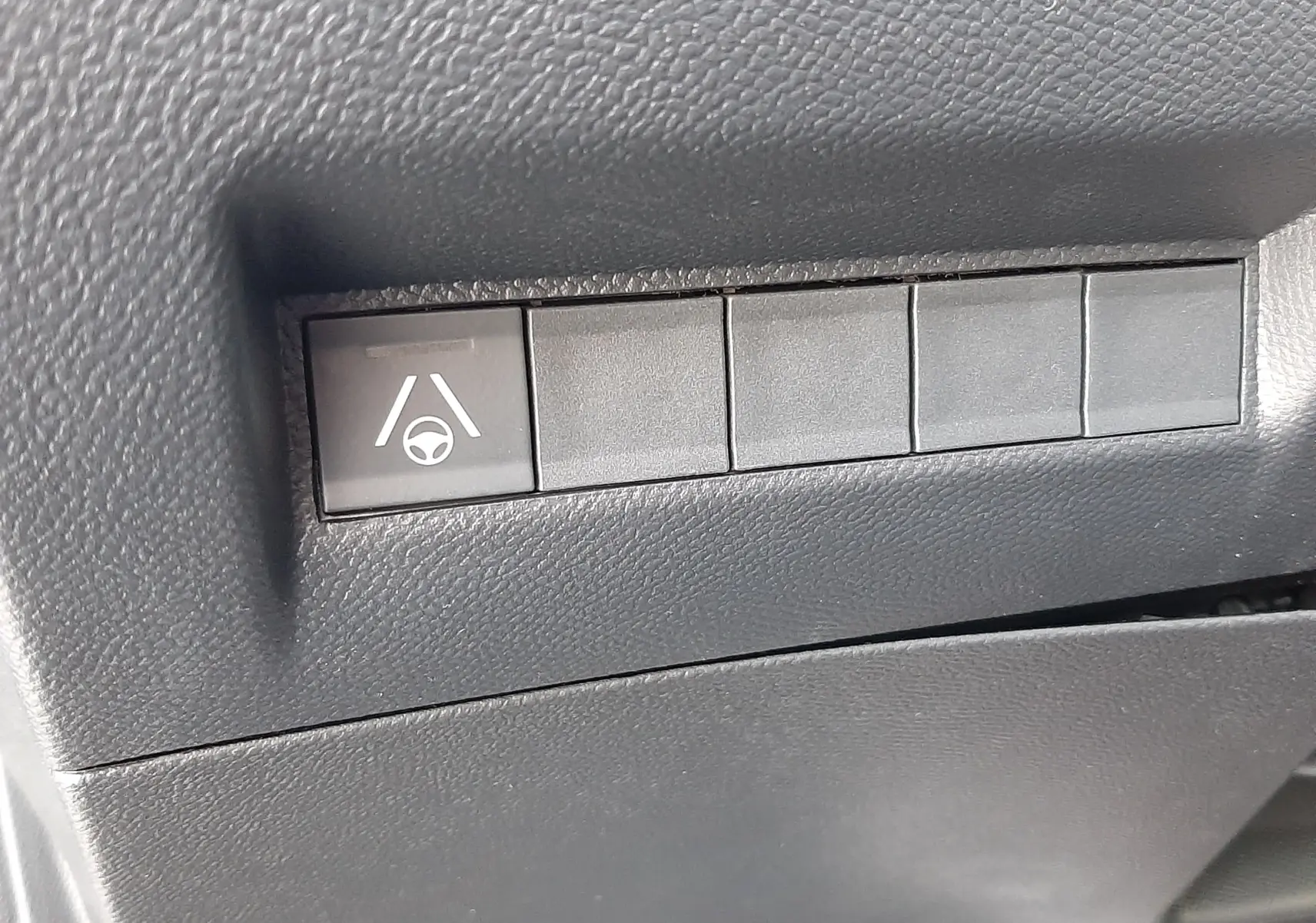 Gros plan sur le bouton d'aide au maintien de voie dans l'habitacle noir d'une Peugeot 208 Hybrid 145ch GT 2026.