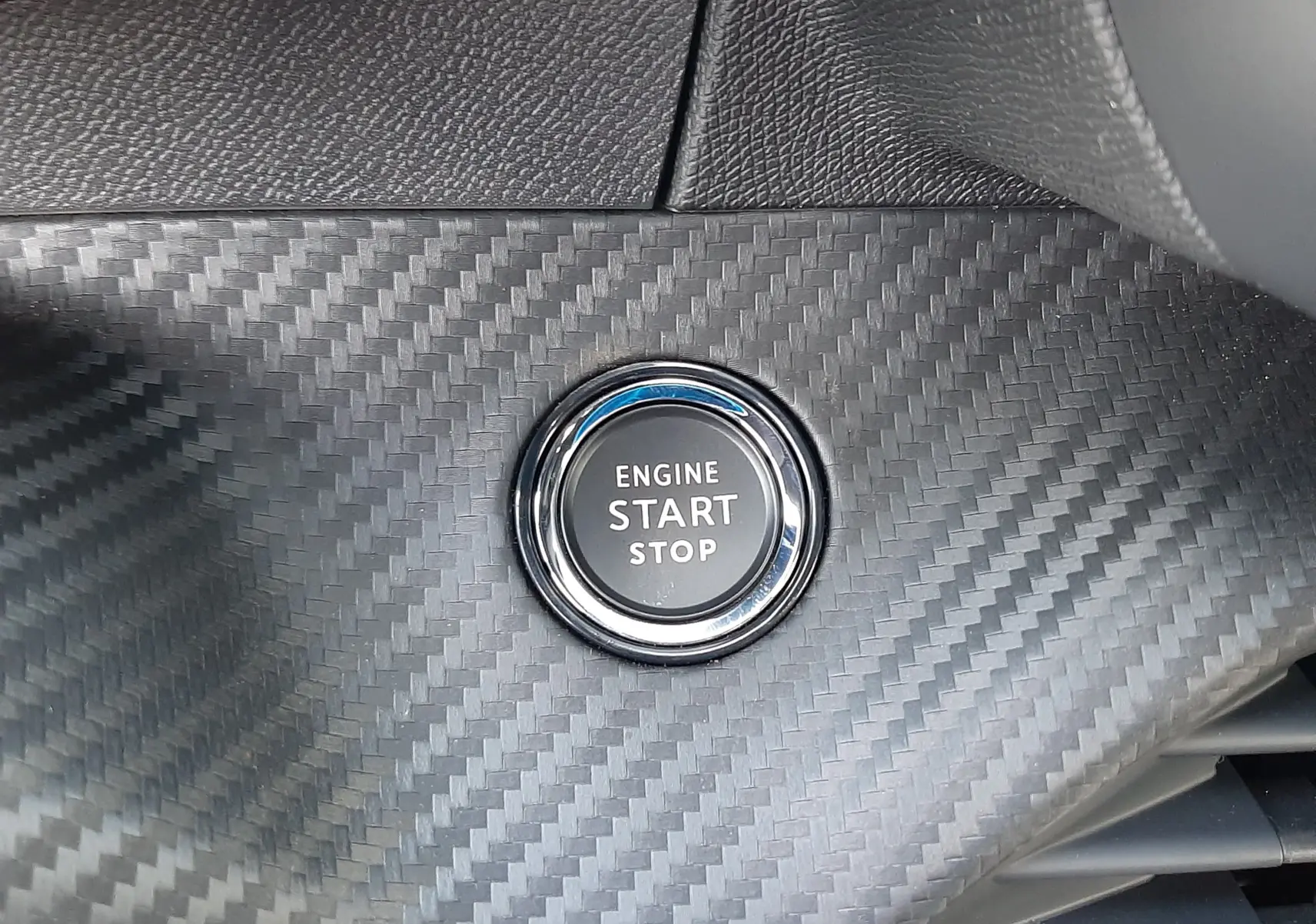 Bouton start/stop moteur sur tableau de bord en finition carbone du Peugeot 208 Hybrid 145ch GT 2026.