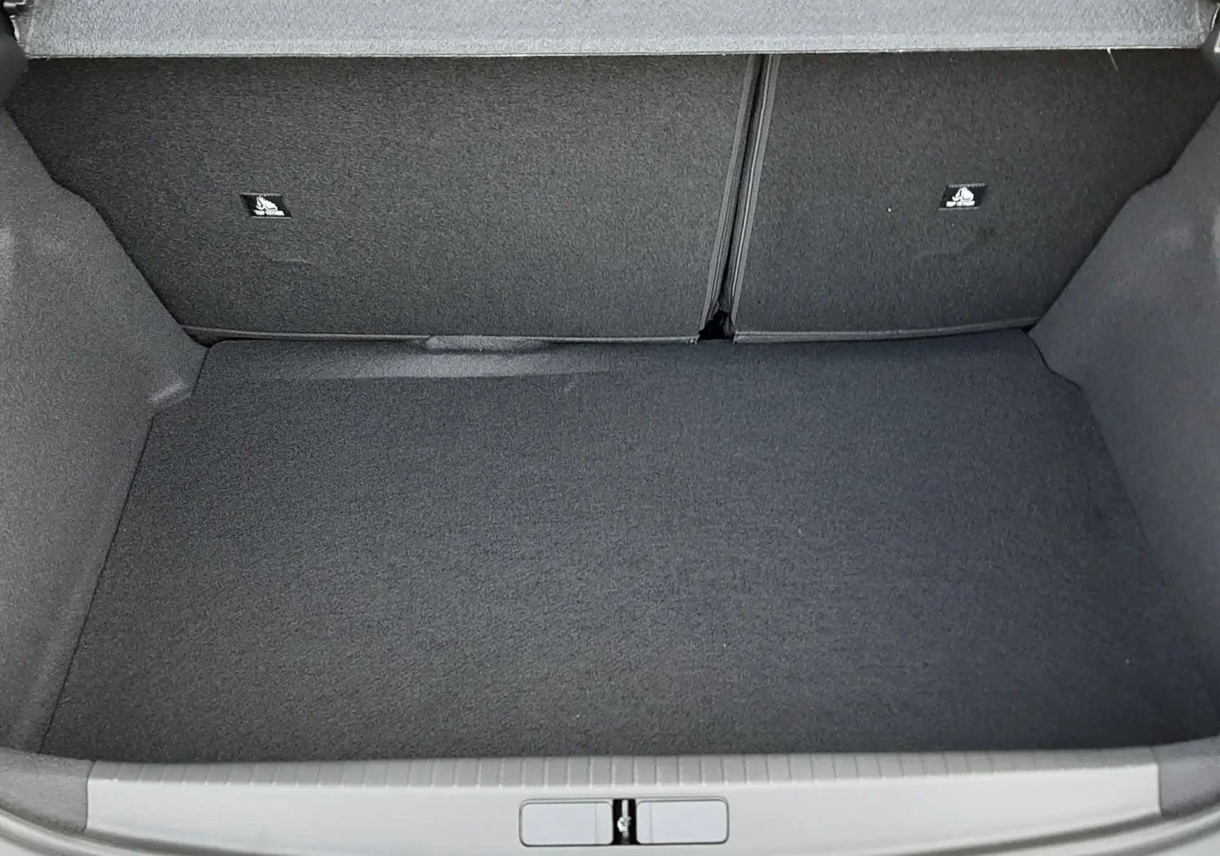 Vue 3/4 arrière droite d'une Peugeot 208 Hybrid 145ch GT noire perla avec gouttes d'eau sur la carrosserie.