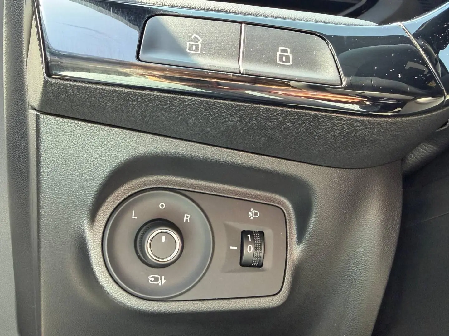 Détail des commandes de réglage des rétroviseurs et des phares sur le côté gauche intérieur d'un MG3 blanc 2025.