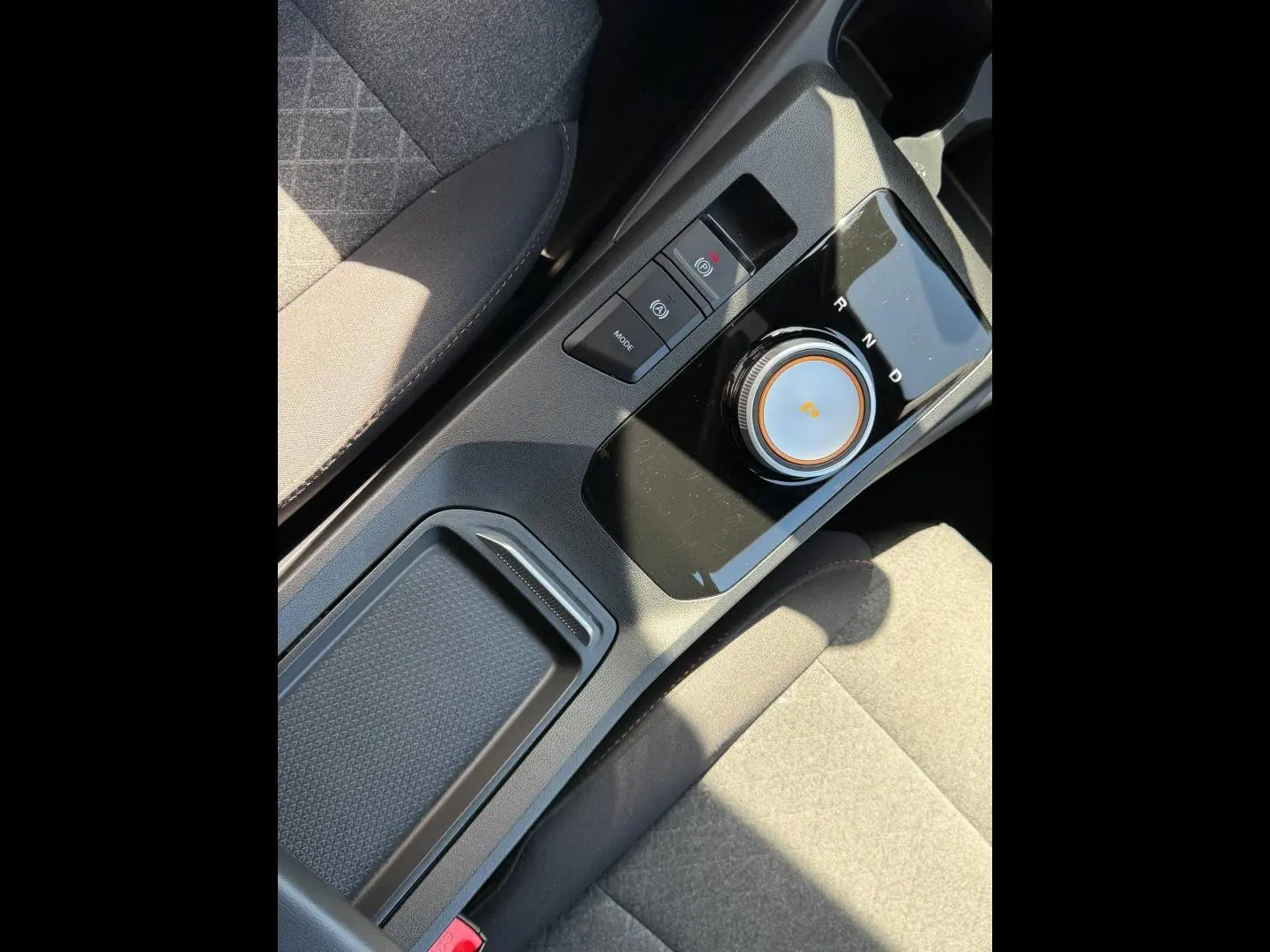 Vue rapprochée de la console centrale noire avec molette de boîte auto et tissu gris du siège MG3 blanc 2025.