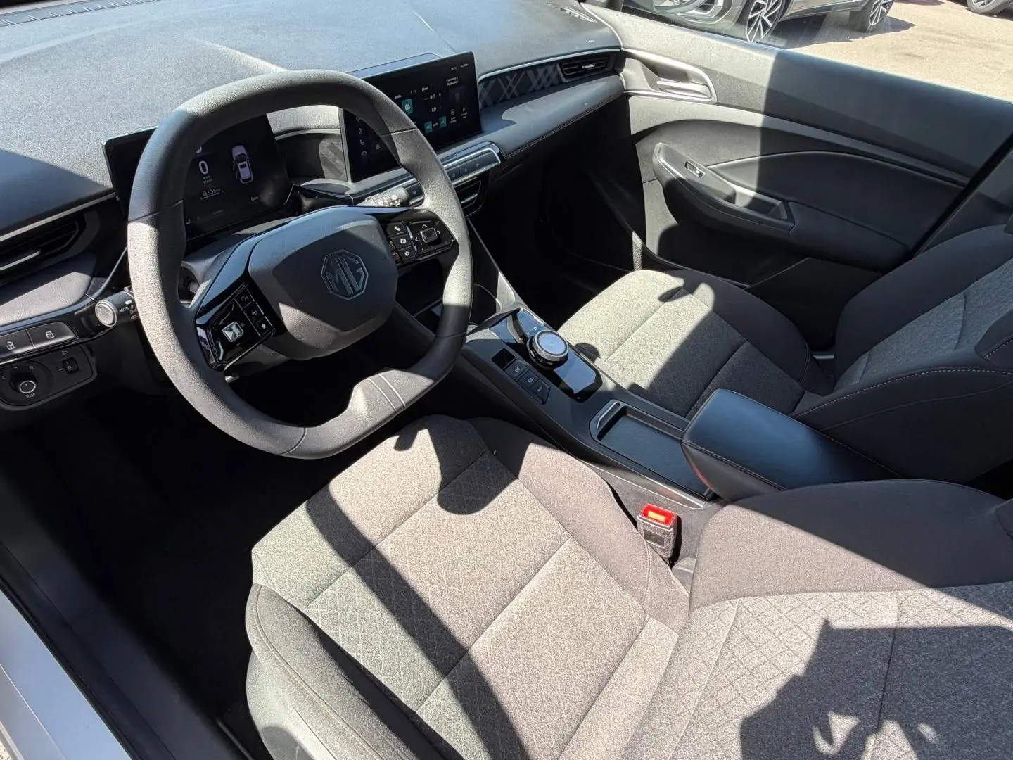 Vue intérieure côté conducteur du MG3 1.5 Hybrid+ 2025, sièges tissu gris et tableau de bord moderne avec écran tactile.