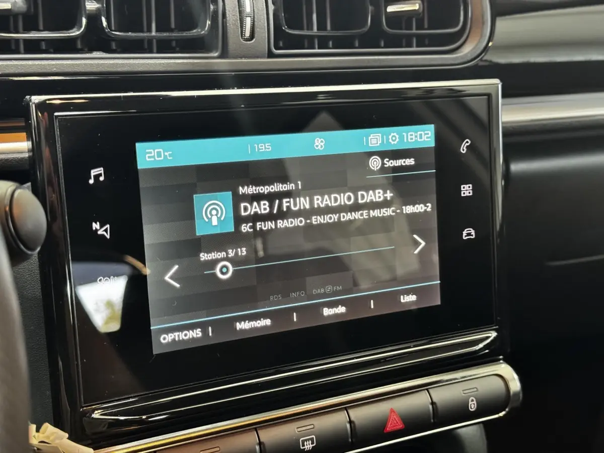 Écran tactile central de 7 pouces affichant la radio DAB dans l’habitacle noir de la Citroën C3 blanche, vue rapprochée.
