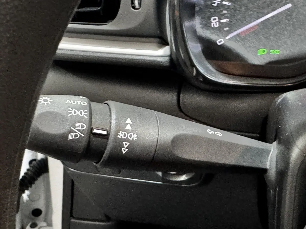 Gros plan sur la manette de clignotants noire du tableau de bord d'une Citroën C3 blanche, version 2024.