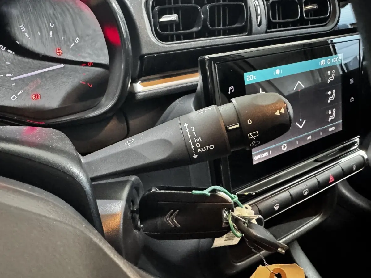 Gros plan intérieur sur le tableau de bord et la clé de contact d’une Citroën C3 blanche, avec écran tactile et commandes au volant.