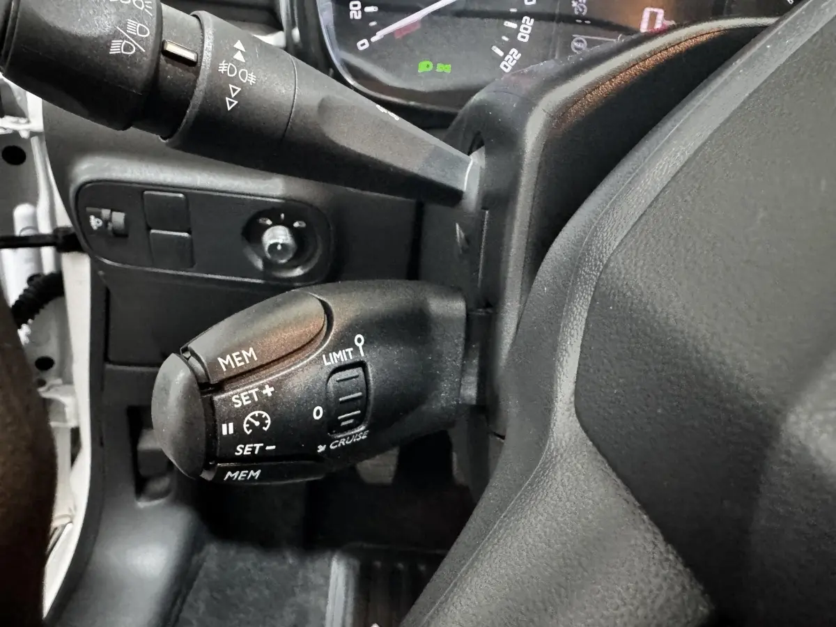 Gros plan sur la commande de régulateur de vitesse à gauche du volant dans une Citroën C3 blanche 2024.