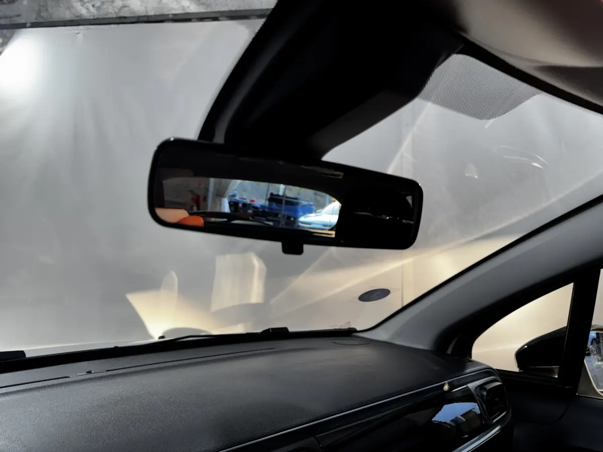 Vue intérieure du tableau de bord noir et du rétroviseur central d'une Citroën C3 blanche 2024.