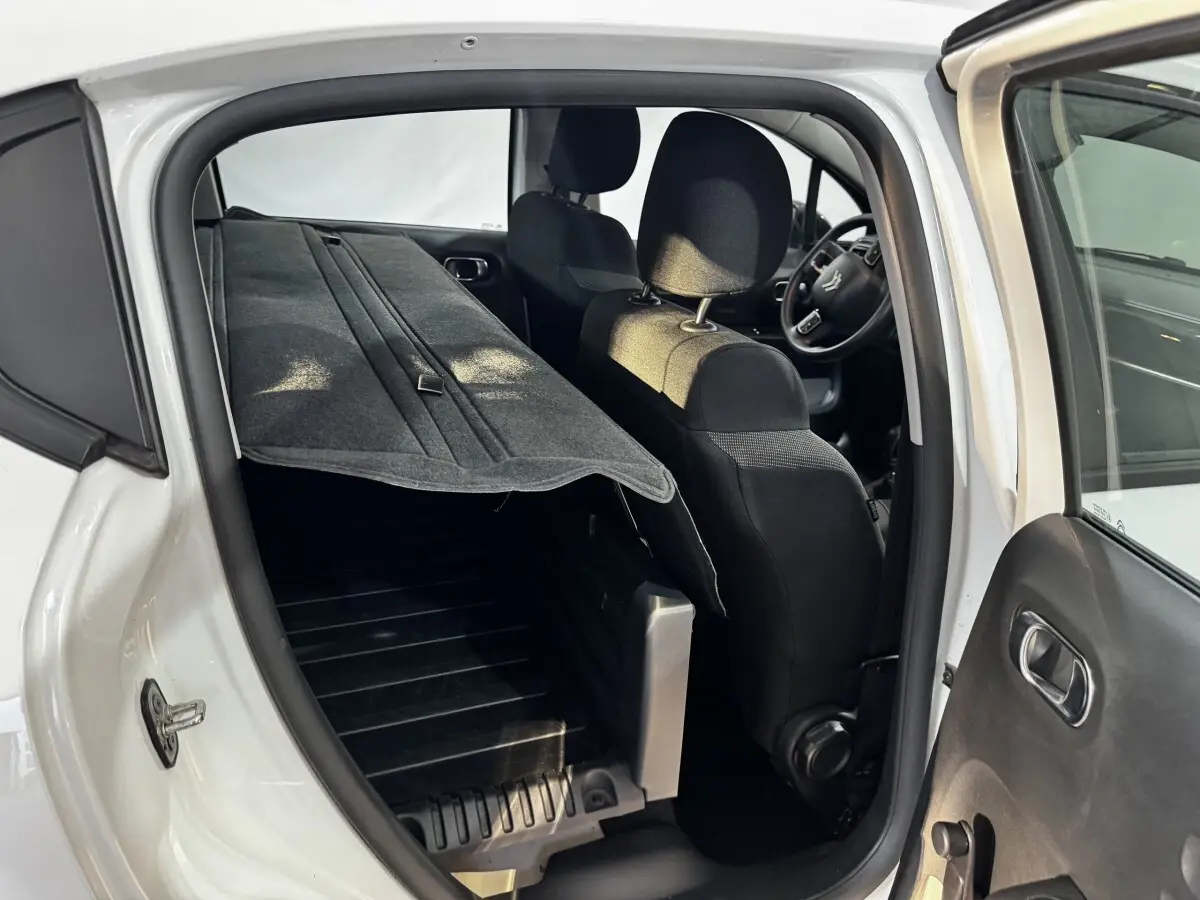 Vue intérieure côté droit d'une Citroën C3 blanche 2024 avec siège arrière rabattable et plancher de coffre visible.