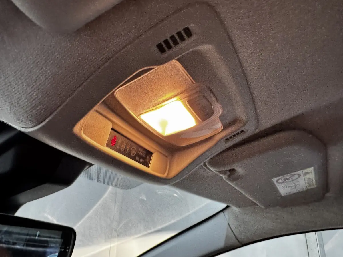 Plafonnier intérieur allumé de la Citroën C3 blanche 2024, vue en gros plan sous le toit côté conducteur.