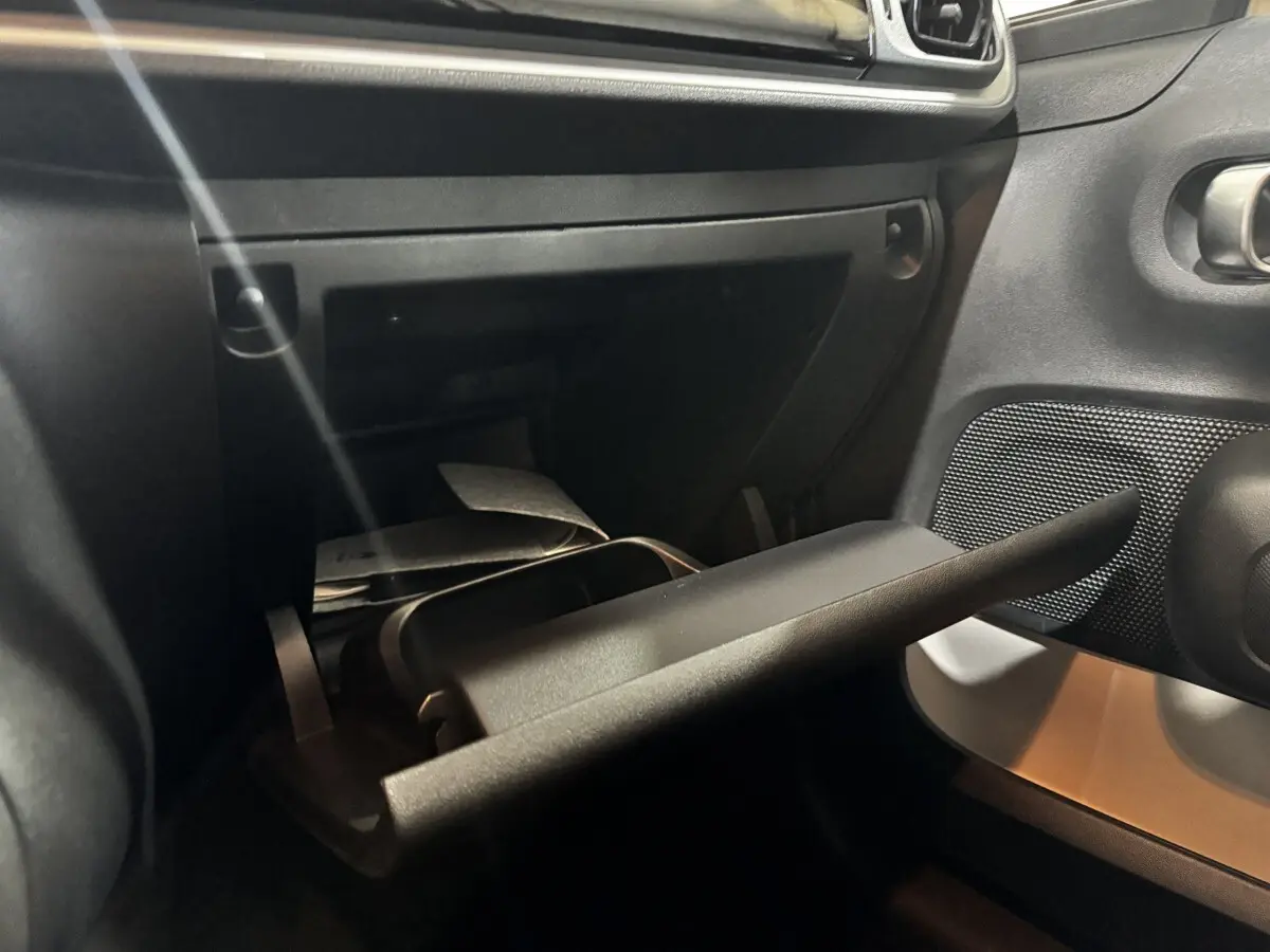 Vue intérieure rapprochée de la boîte à gants ouverte côté passager de la Citroën C3 blanche, montrant des documents à l’intérieur.