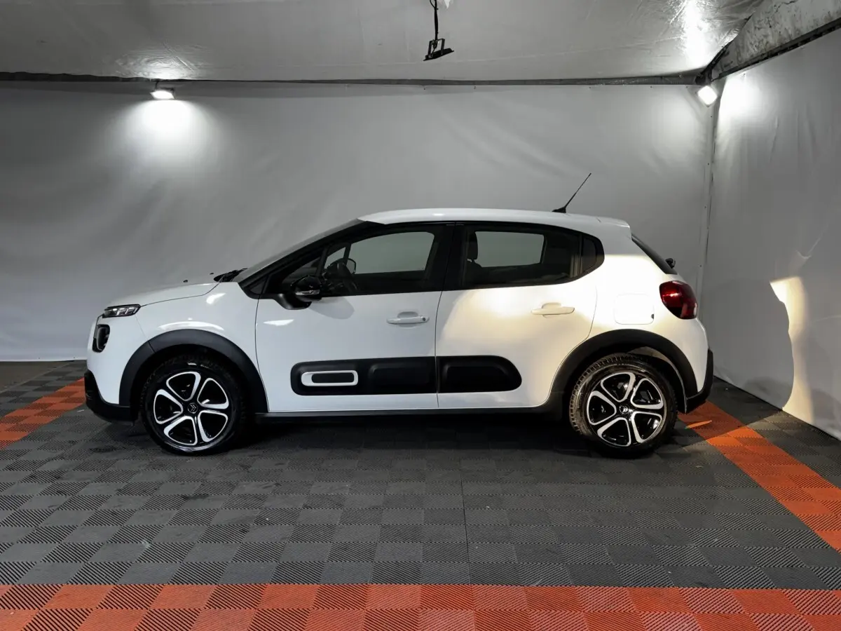 Vue de profil côté gauche d'une Citroën C3 blanche avec protections noires et jantes alliage bicolores.
