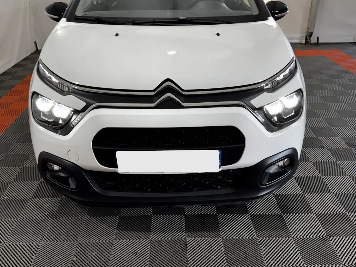 Vue frontale d'une Citroën C3 blanche 2024 avec phares LED allumés et calandre noire distinctive.