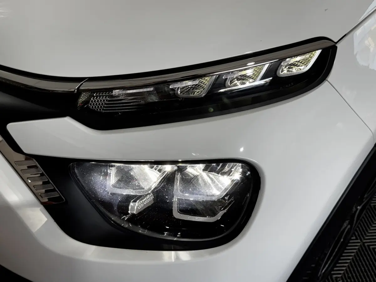 Gros plan sur le phare avant droit blanc de la Citroën C3 2024 avec éclairage LED distinctif et détails noirs.