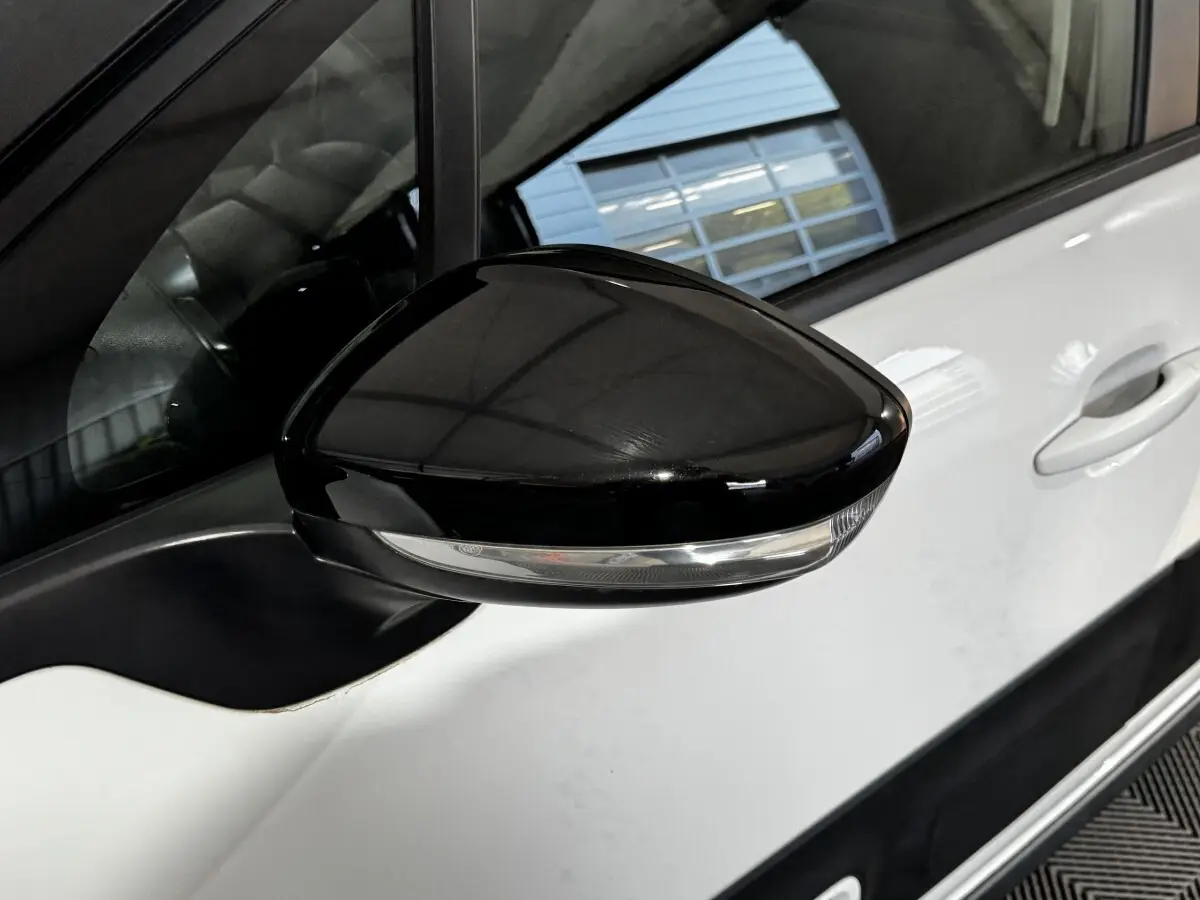 Gros plan sur le rétroviseur droit noir avec clignotant intégré d'une Citroën C3 blanche, vue côté conducteur.