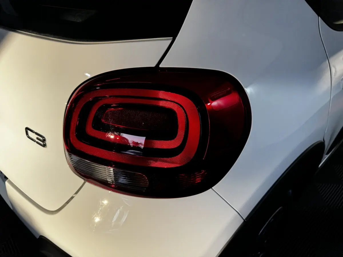 Gros plan sur le feu arrière droit rouge d'une Citroën C3 blanche, avec logo C3 visible sur la malle arrière.