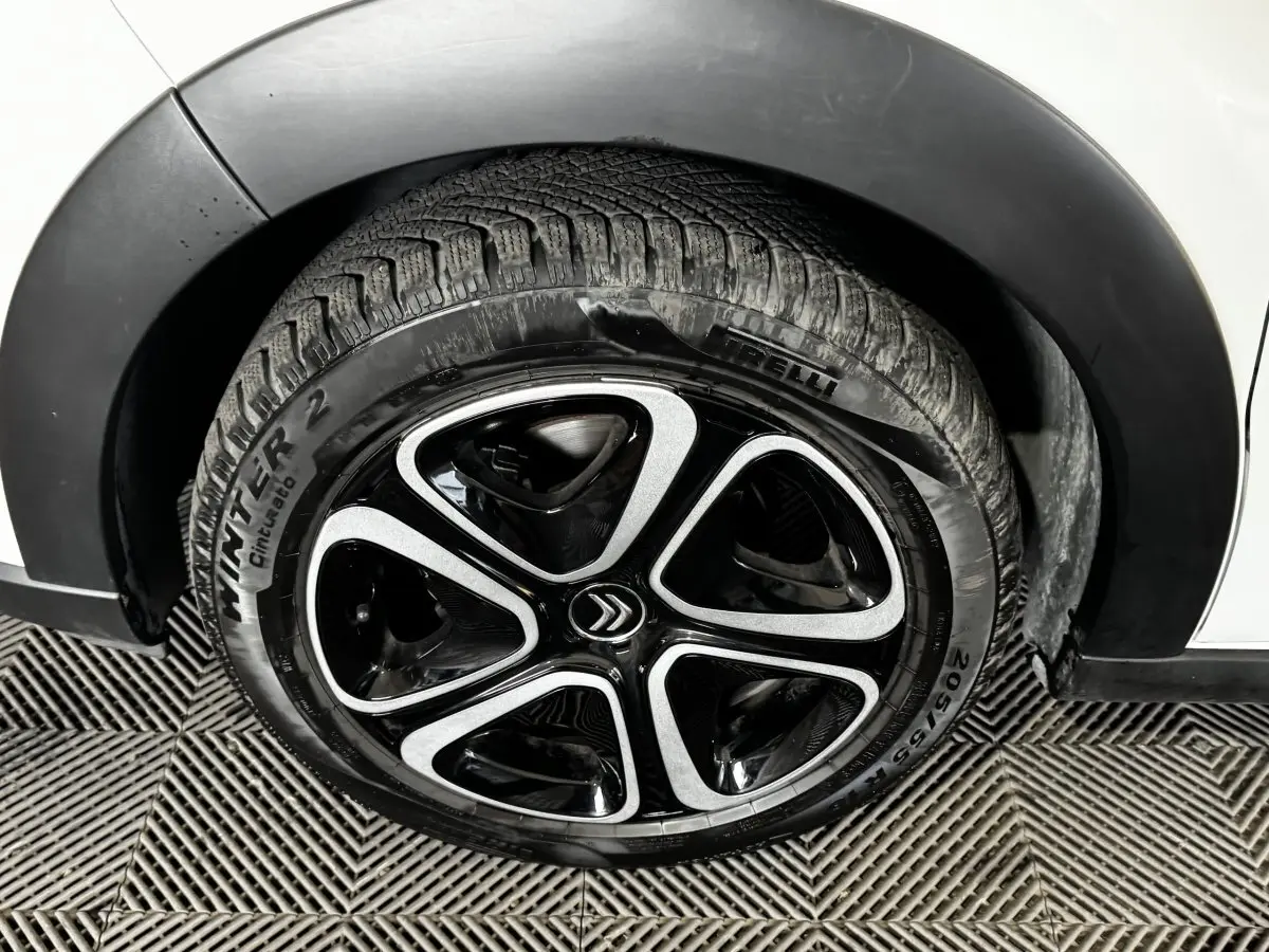 Gros plan sur la roue avant droite d'une Citroën C3 blanche avec jante noire et argentée au design moderne.