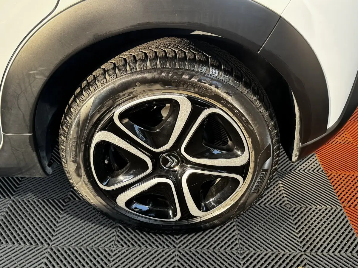 Gros plan sur la roue arrière droite blanche d'une Citroën C3 2024 avec jante noire et argentée au design distinctif.