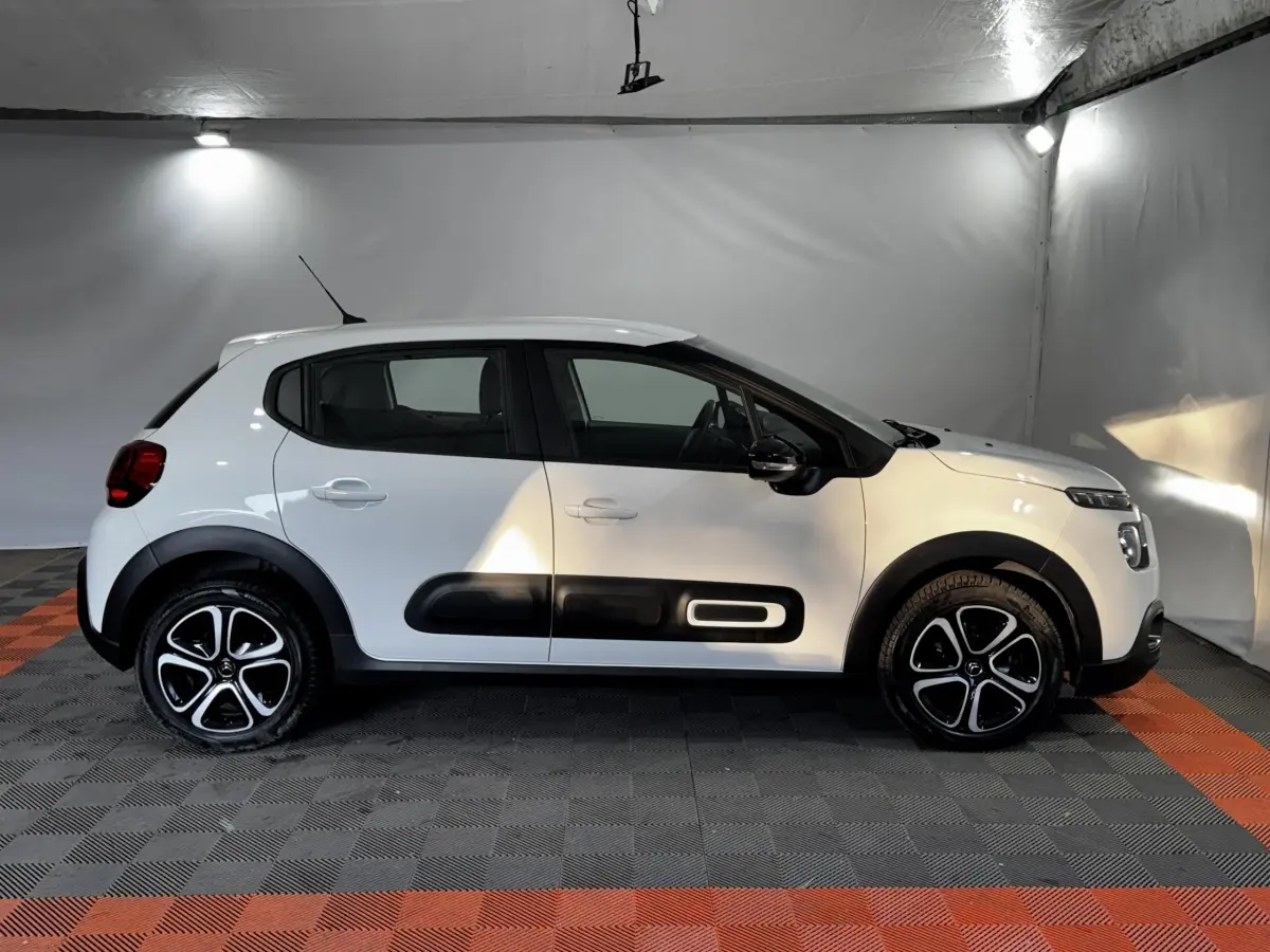 Citroën C3 blanche vue de profil côté gauche, avec protections noires distinctives sur les portières.