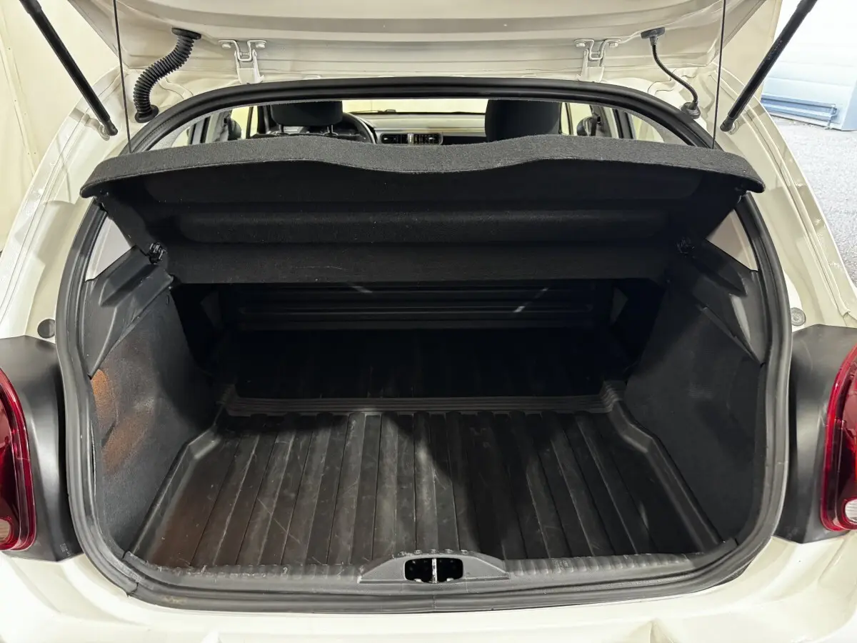 Coffre ouvert vu de l'arrière d'une Citroën C3 blanche 2024, montrant l'espace de chargement vide et la trappe de séparation.