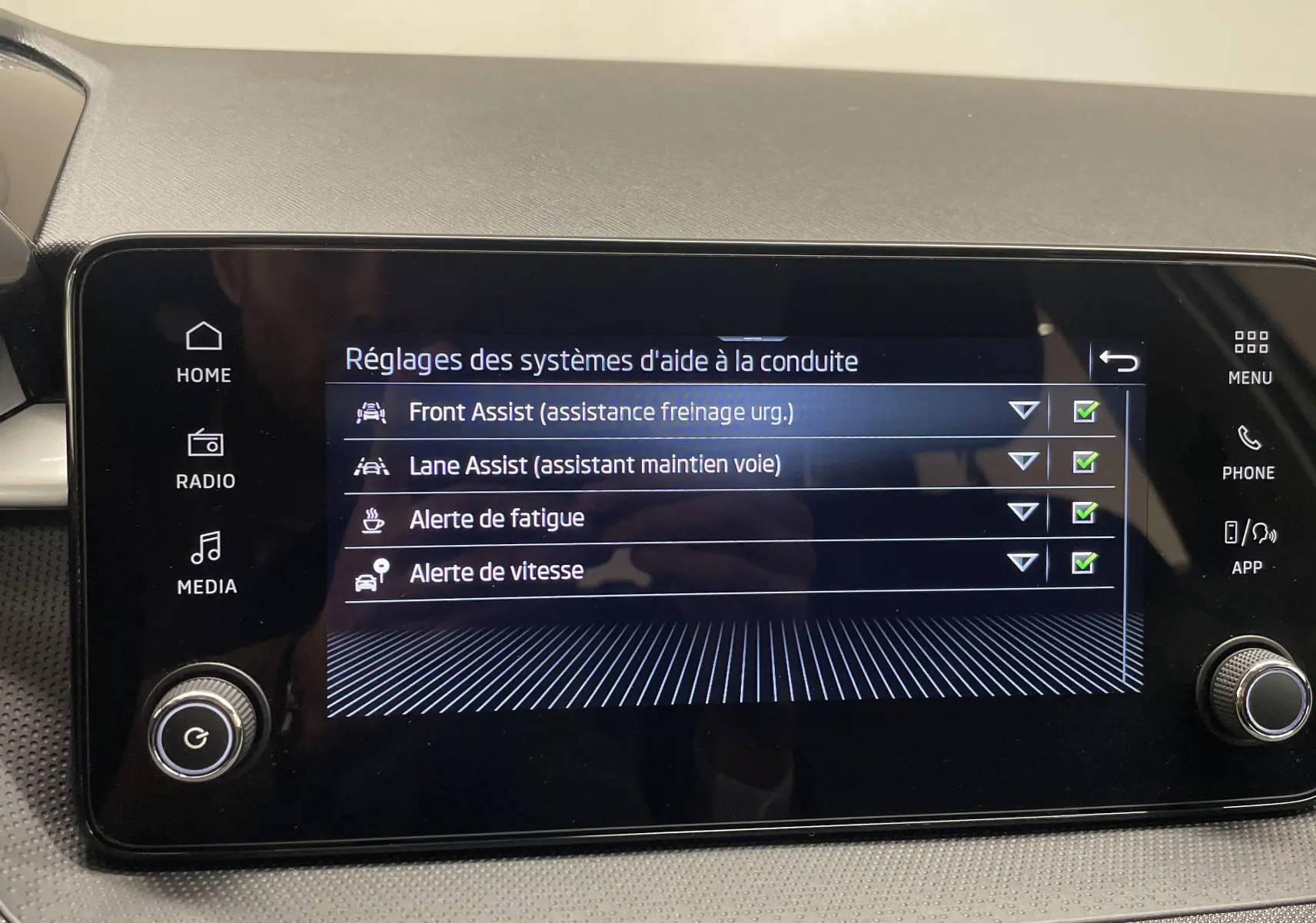 Écran tactile central de la Skoda Fabia 2025 affichant les réglages des aides à la conduite avec menu clair et boutons physiques.