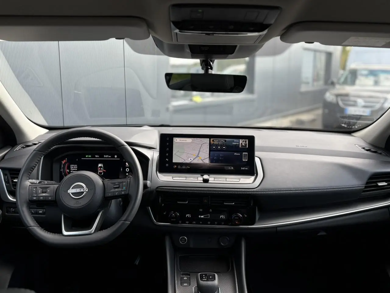 Intérieur du Nissan Qashqai 2024 vu de face, tableau de bord noir avec écran tactile central et volant cuir.