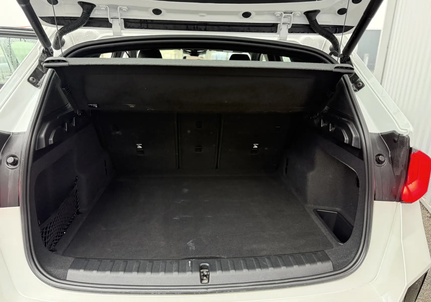 Écran tactile central du tableau de bord d’un BMW X1 blanc minéral, affichant les applications connectées.