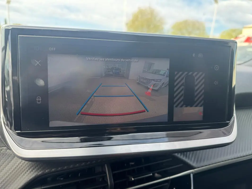 Écran tactile intérieur montrant la caméra de recul avec guidage, tableau de bord de Peugeot 2008 blanc 2024.