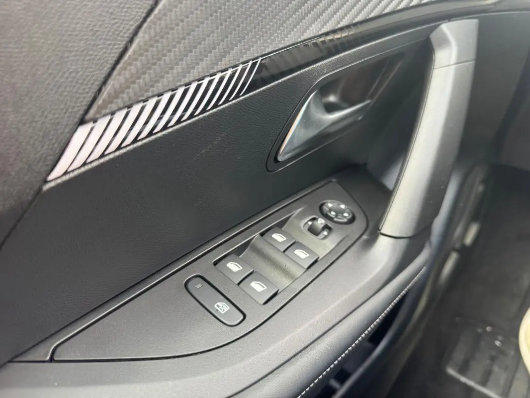 Vue rapprochée de la porte côté gauche du Peugeot 2008 blanc 2024, avec commandes des vitres électriques et rétroviseurs.