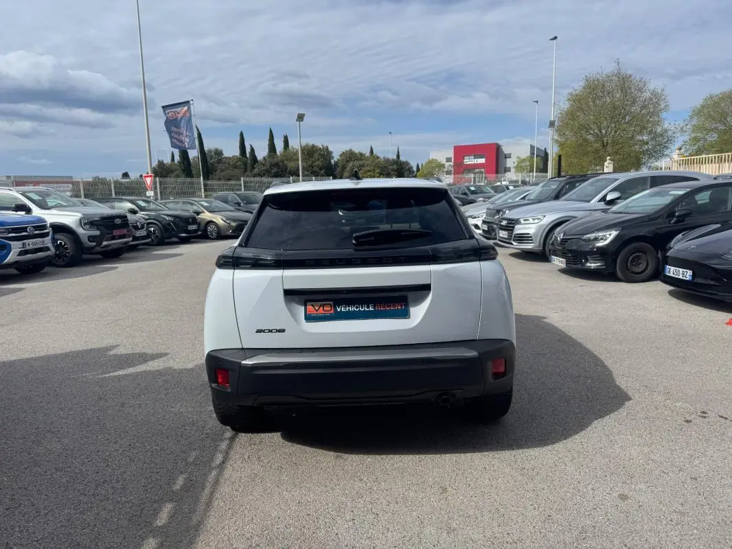 Vue arrière d’un Peugeot 2008 blanc 2024 avec barres de toit et jantes alliage 17 pouces, stationné en extérieur.