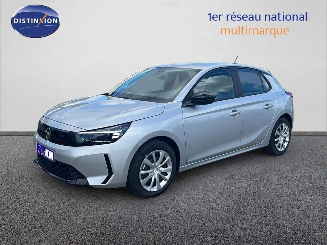 Opel Corsa gris 2025 vue 3/4 avant droit, avec calandre noire et jantes alliage, stationnée devant un mur clair.