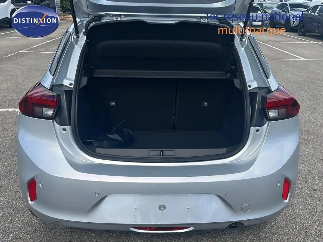 Vue arrière d'une Opel Corsa gris clair 2025 avec coffre ouvert, feux arrière allumés et capot de coffre relevé.