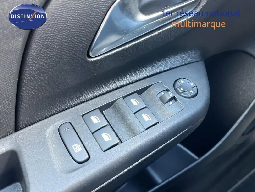 Gros plan sur les commandes des vitres électriques et rétroviseurs sur la porte côté conducteur de l’Opel Corsa gris 2025.