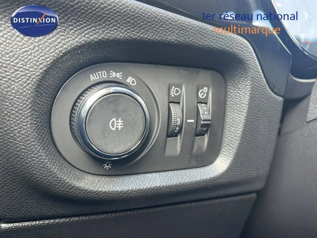 Gros plan sur le bouton de commande des phares et réglages lumineux dans l'habitacle de l'Opel Corsa gris.