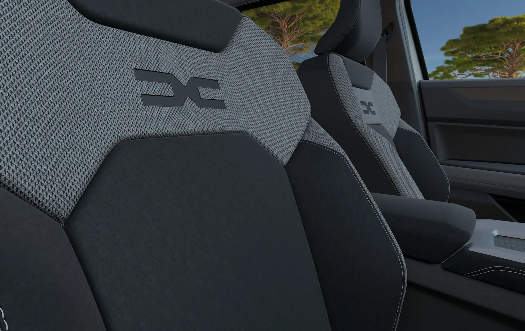 Gros plan sur les sièges avant gris et noirs du Dacia Bigster Hybrid 155 Journey avec logo distinctif brodé.