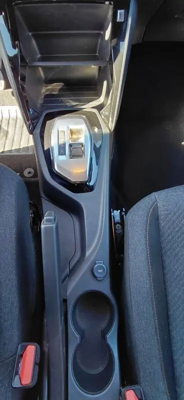 Vue plongeante sur la console centrale noire du Peugeot 2008 Hybrid 136 e-DCS6 Style avec levier de vitesse et porte-gobelets.