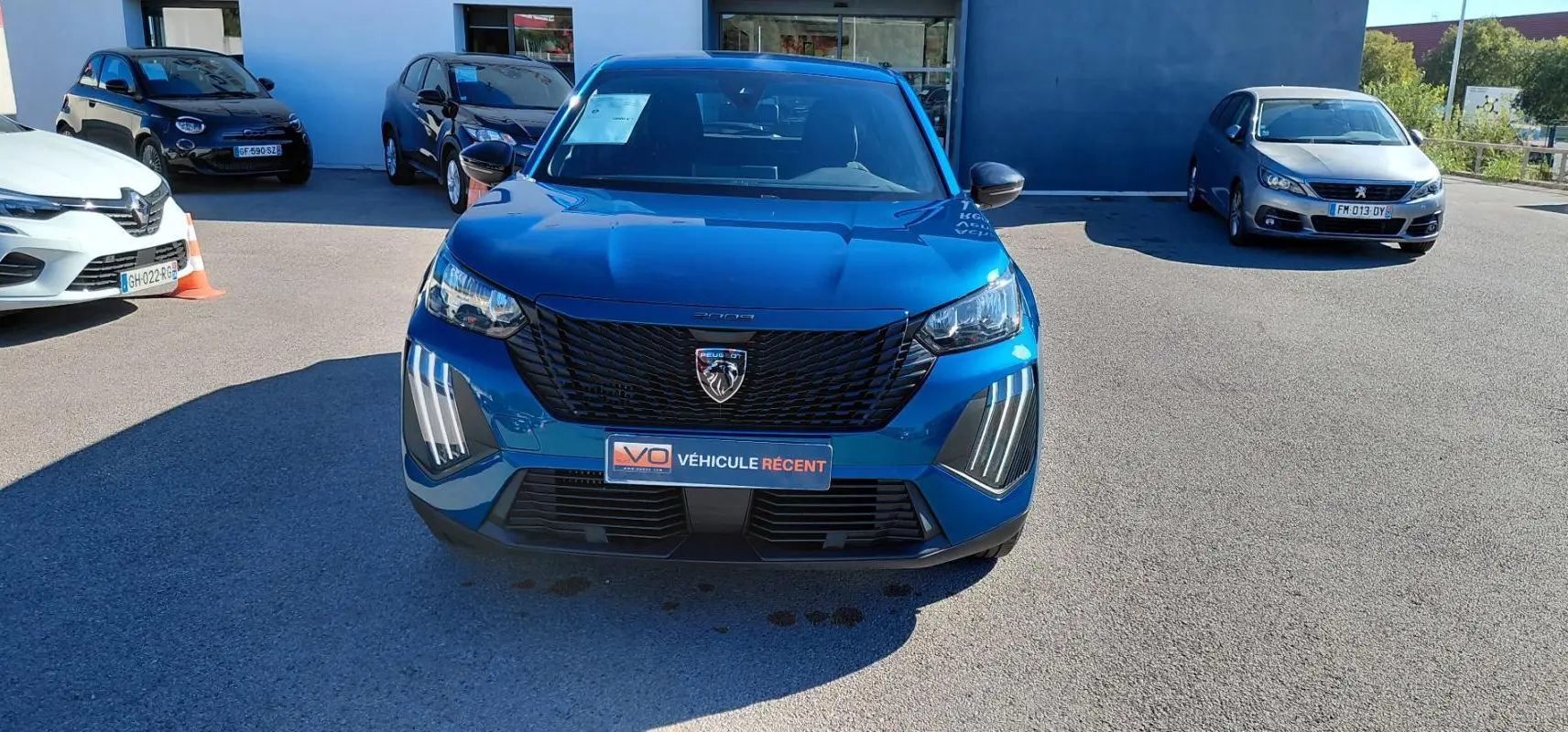 Peugeot 2008 Hybrid bleu vue de face, avec calandre noire et feux LED verticalisés distinctifs.