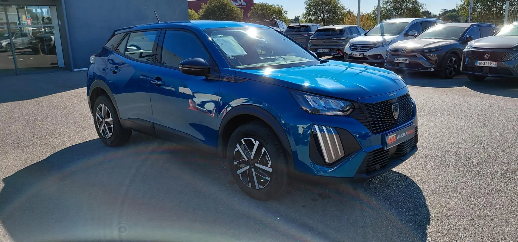 Peugeot 2008 Hybrid bleu en 3/4 avant droit, avec jantes 16 pouces et calandre noire distinctive.