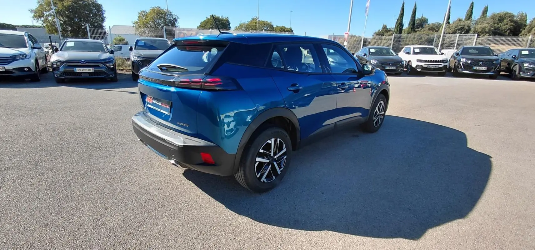 Peugeot 2008 Hybrid bleu en 3/4 arrière droit, avec jantes 16 pouces et feux arrière LED distinctifs.