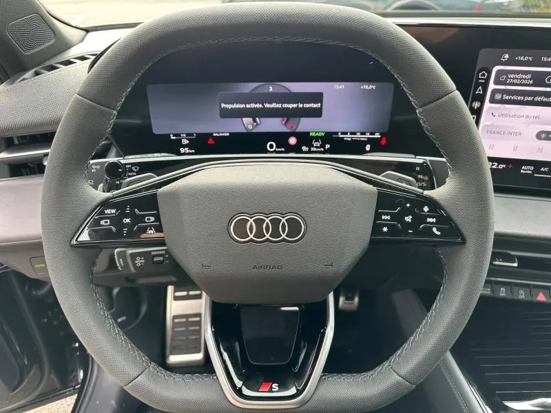 Vue rapprochée du volant sport en cuir noir avec commandes multifonctions et tableau de bord numérique d’un Audi Q3 noir Mythique.