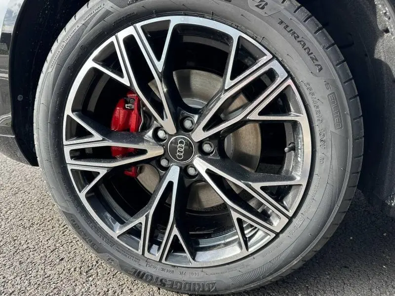 Gros plan sur la jante alu noire et argentée avec étrier de frein rouge d’un Audi Q3 Noir Mythique métallisé.