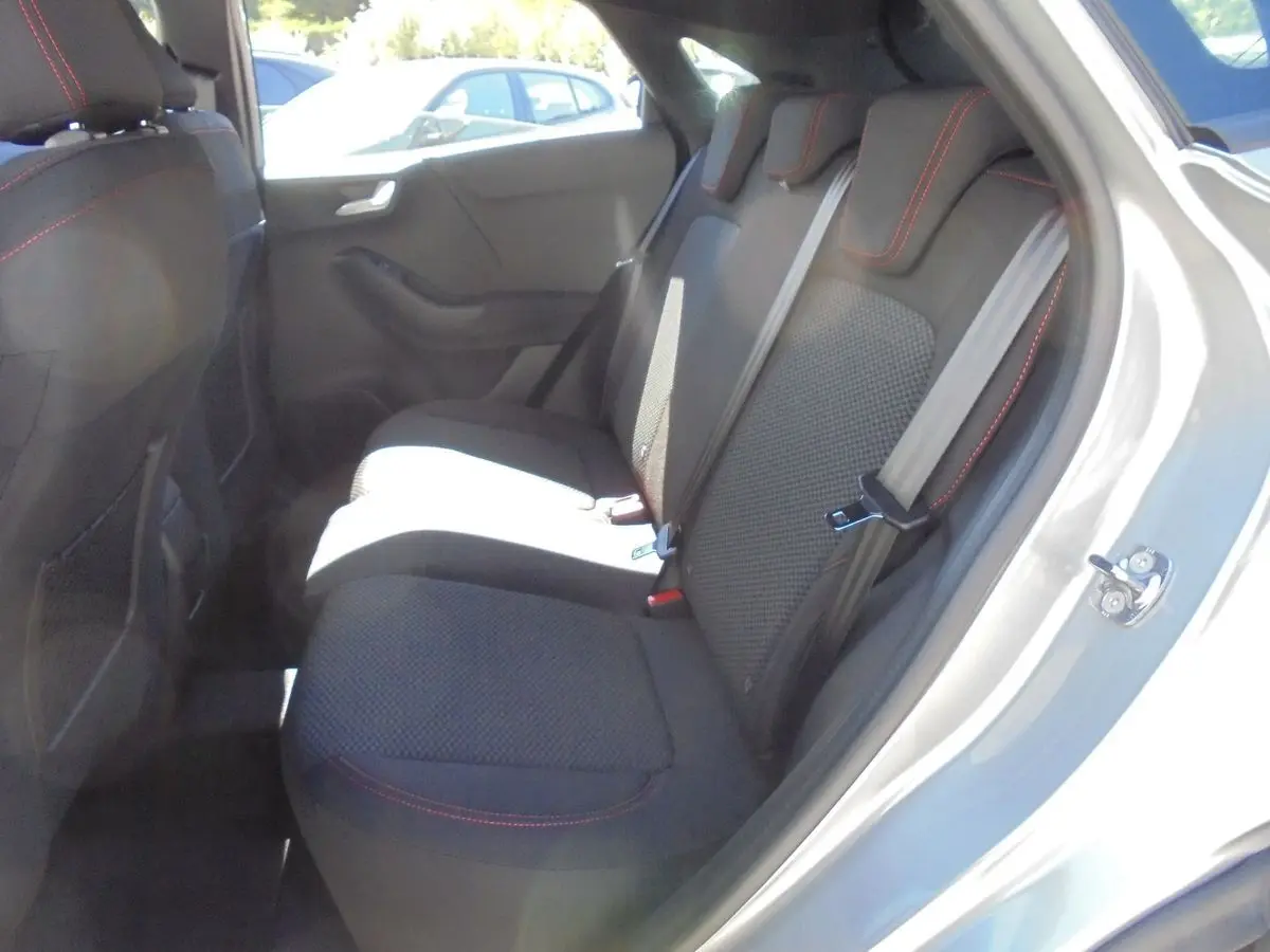 Vue côté droit de l'habitacle arrière du Ford Puma gris Solar Metal avec sièges tissu noir et surpiqûres rouges.