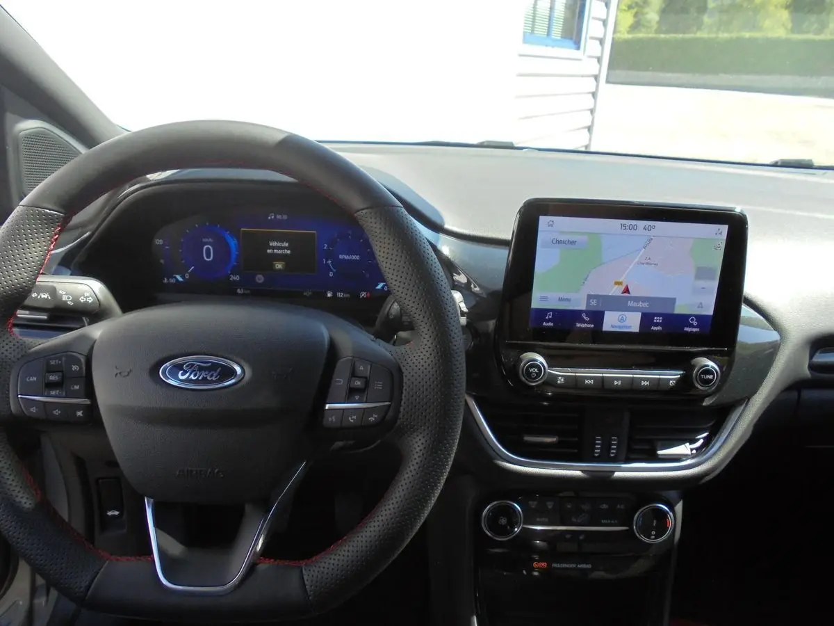Vue intérieure centrée sur le volant et l'écran tactile du Ford Puma gris Solar Metal 2022 avec navigation affichée.
