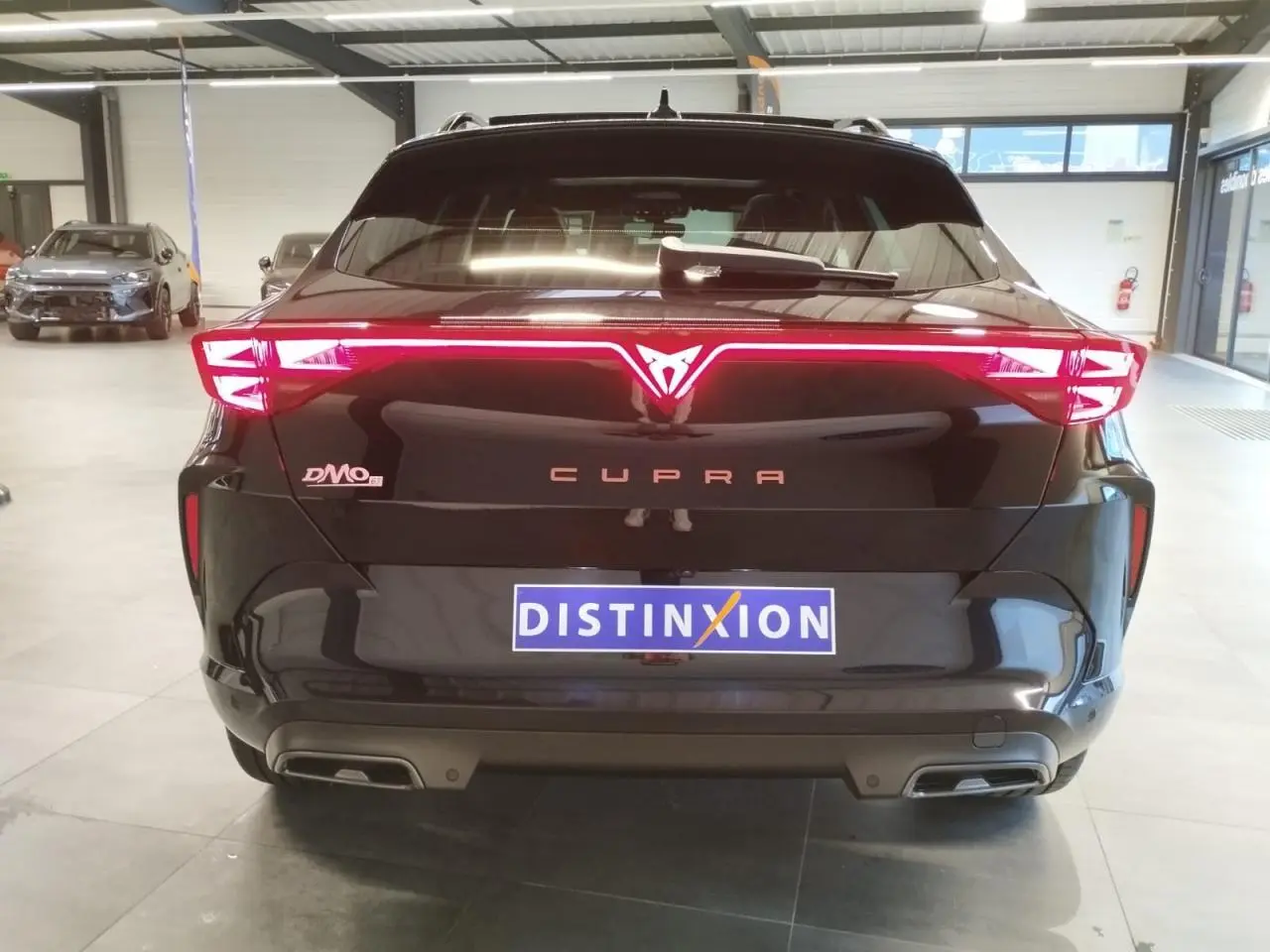 Vue arrière d'une CUPRA Formentor noire métal avec feux arrière Tri-LED et double sortie d'échappement noire.