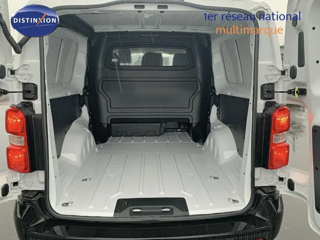 Vue arrière du Peugeot Expert Fourgon blanc 2023 avec portes ouvertes montrant l’espace de chargement vide et la cabine approfondie.